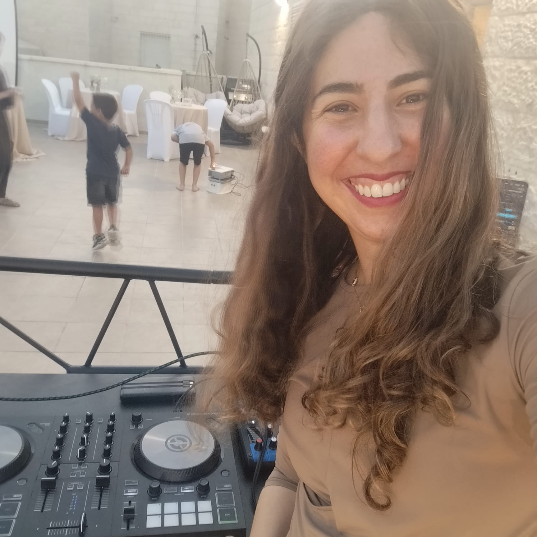 DJ Shira smiling beside her mixing deck
